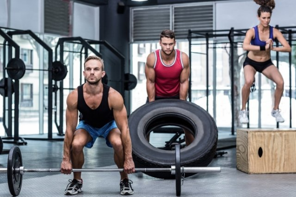 3 pessoas num box de crossfit praticando exercício