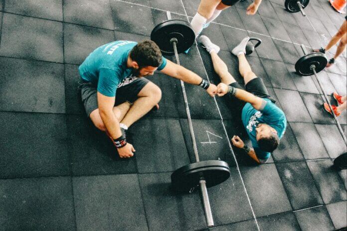 imagem mostrando dois homens se ajudando no crossfit